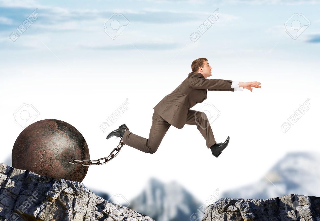 Businessman with iron ballast  hopping over bottomless pit